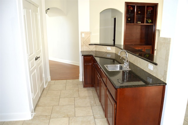 kitchen with decorative backsplash, light tile patterned floors, sink, and dark stone counters