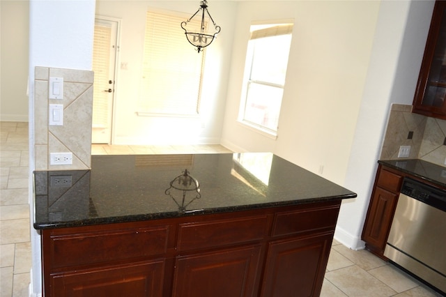 kitchen featuring backsplash, stainless steel dishwasher, pendant lighting, a notable chandelier, and dark stone countertops