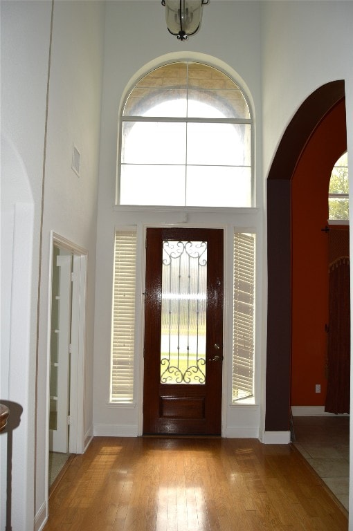 entryway featuring a towering ceiling and light wood-type flooring