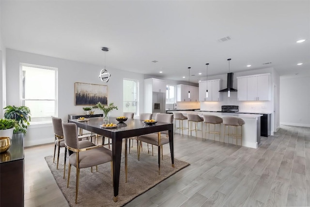 dining room featuring a wealth of natural light, sink, and light hardwood / wood-style floors