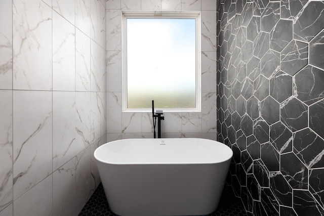 bathroom featuring a tub to relax in and tile walls