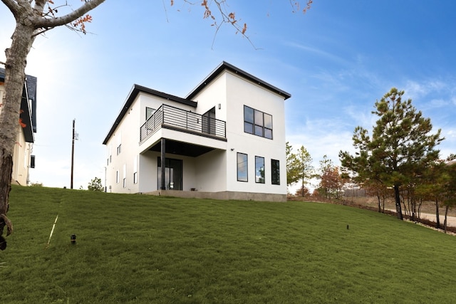 rear view of house with a yard and a balcony