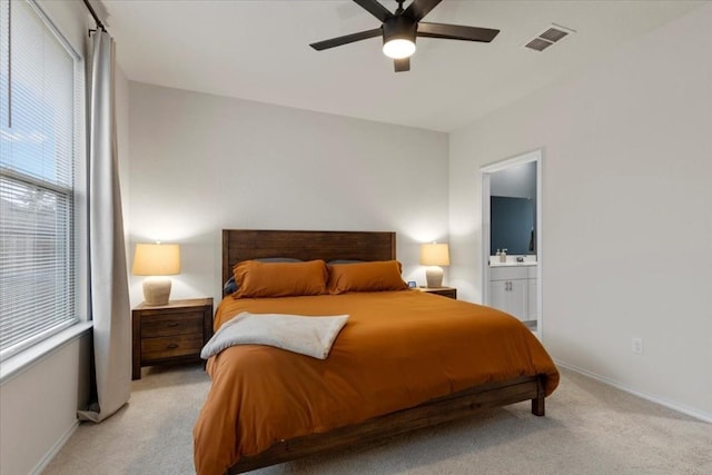 bedroom with multiple windows, ceiling fan, connected bathroom, and light carpet