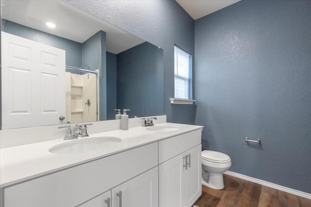 808 Beacon Hts, Seguin, TX 78155 - bathroom with wood finished floors, toilet, double vanity, a textured wall, and a shower