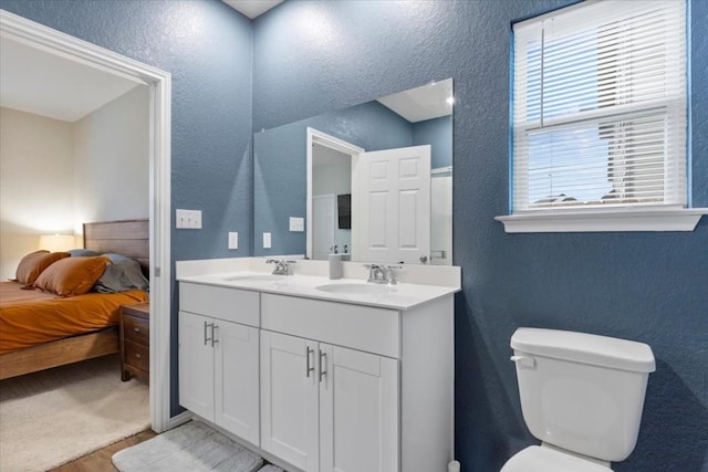 808 Beacon Hts, Seguin, TX 78155 - ensuite bathroom featuring a textured wall, double vanity, wood finished floors, and toilet