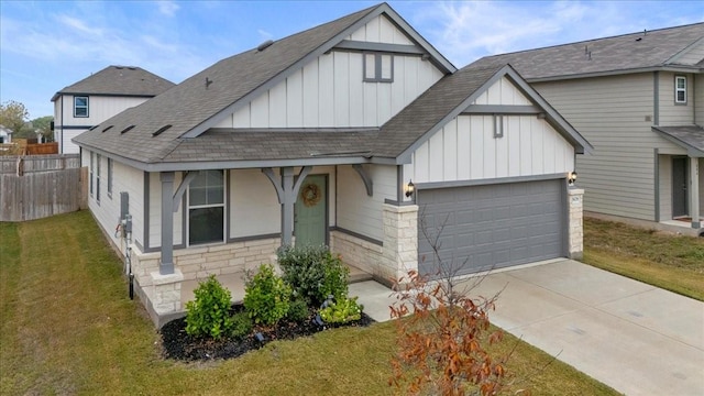 view of front of home with roof with shingles, a front lawn, concrete driveway, a garage, and board and batten siding