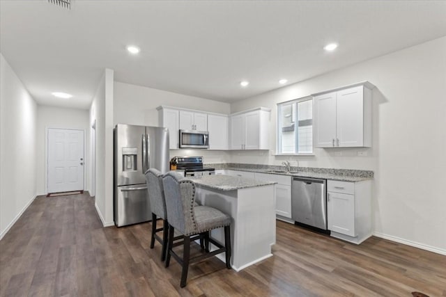 808 Beacon Hts, Seguin, TX 78155 - kitchen featuring stainless steel appliances, a breakfast bar area, white cabinets, a center island, and dark wood-type flooring