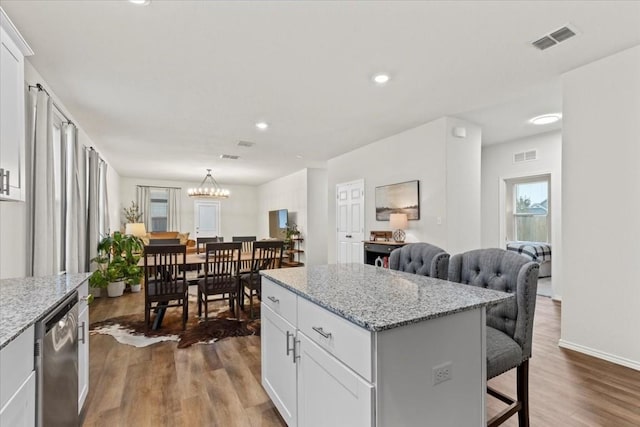 kitchen featuring white cabinetry, a kitchen island, dishwasher, and a kitchen breakfast bar