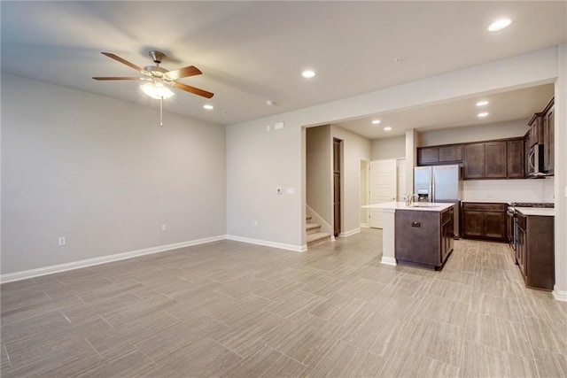 kitchen featuring dark brown cabinetry, ceiling fan, a center island with sink, and stainless steel appliances