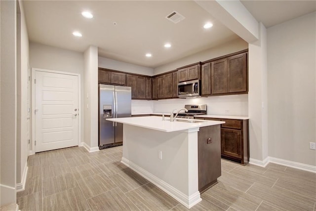 kitchen with dark brown cabinets, stainless steel appliances, a center island with sink, and sink