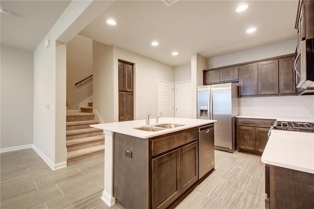 kitchen featuring dark brown cabinets, stainless steel appliances, a kitchen island with sink, and sink