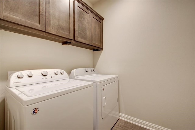 laundry room featuring washer and clothes dryer, dark hardwood / wood-style flooring, and cabinets