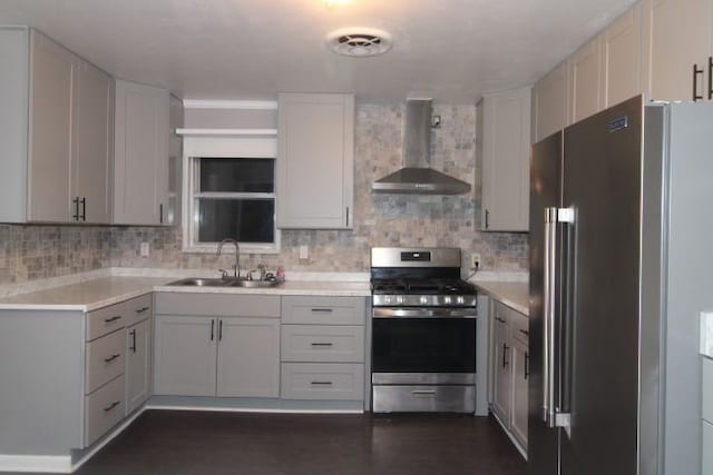 kitchen with appliances with stainless steel finishes, backsplash, wall chimney exhaust hood, sink, and dark hardwood / wood-style floors