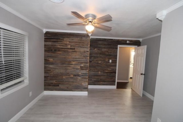 spare room with hardwood / wood-style flooring, ceiling fan, wood walls, and ornamental molding