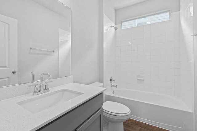 full bathroom with hardwood / wood-style floors, vanity, toilet, and tiled shower / bath