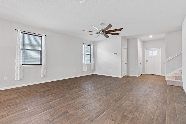 unfurnished living room featuring ceiling fan, dark hardwood / wood-style flooring, and a textured ceiling