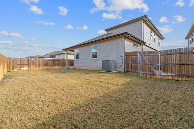 rear view of property with central air condition unit and a yard