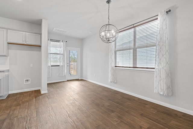 unfurnished dining area featuring a chandelier and dark hardwood / wood-style flooring