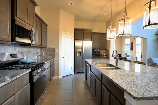 kitchen with sink, tasteful backsplash, decorative light fixtures, a kitchen island with sink, and appliances with stainless steel finishes