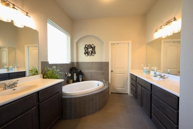 bathroom with tile patterned flooring, vanity, and tiled bath