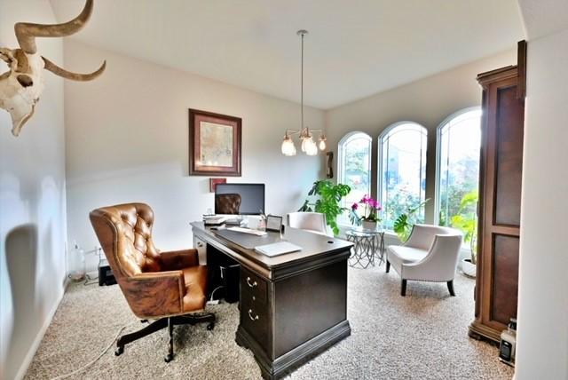 home office with light carpet and an inviting chandelier