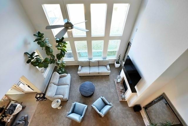 carpeted living room with a towering ceiling and ceiling fan