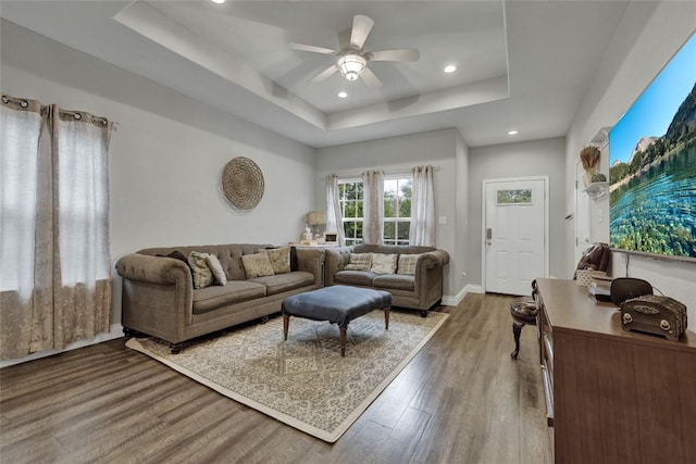 living room featuring a raised ceiling, ceiling fan, and hardwood / wood-style flooring