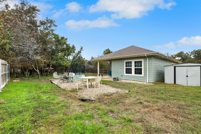 rear view of house featuring a lawn, a patio area, a storage shed, and a trampoline