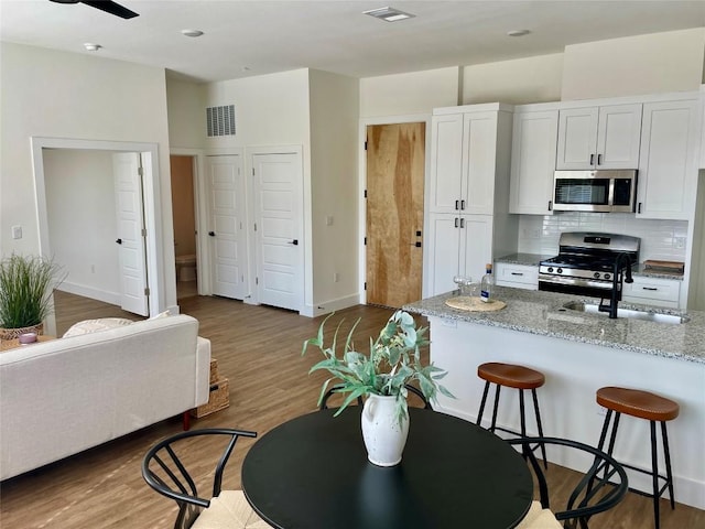 kitchen featuring white cabinets, sink, dark hardwood / wood-style flooring, stainless steel appliances, and light stone counters