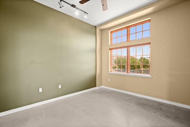 spare room featuring ceiling fan, concrete floors, and track lighting