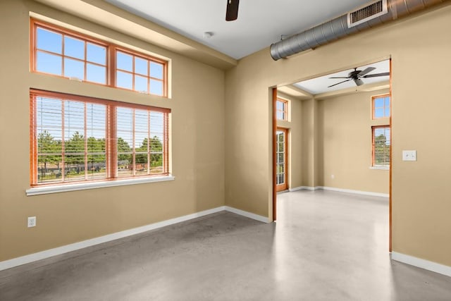 spare room featuring ceiling fan, concrete flooring, and a wealth of natural light