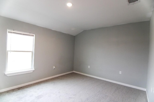 carpeted empty room with vaulted ceiling