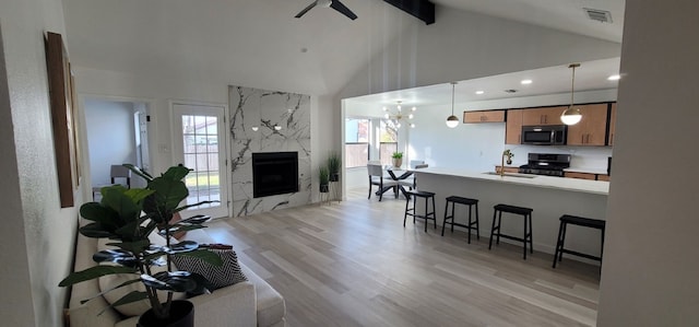 living room with beam ceiling, sink, light hardwood / wood-style flooring, a high end fireplace, and high vaulted ceiling