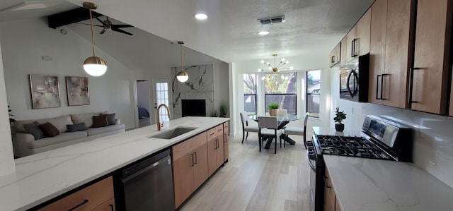 kitchen featuring light stone countertops, light wood-type flooring, stainless steel appliances, sink, and hanging light fixtures