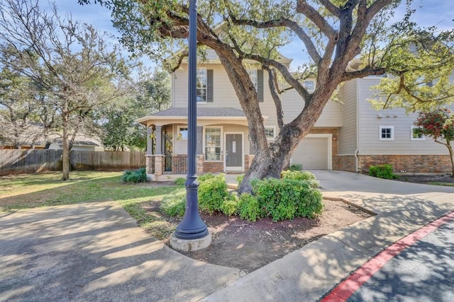 view of front facade with concrete driveway, an attached garage, and fence