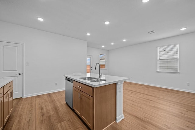 kitchen with dishwasher, sink, light hardwood / wood-style floors, and a center island with sink