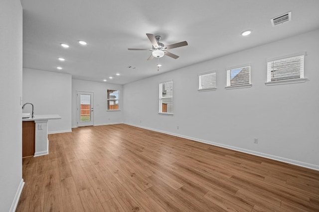 unfurnished living room featuring light wood-type flooring, ceiling fan, and sink