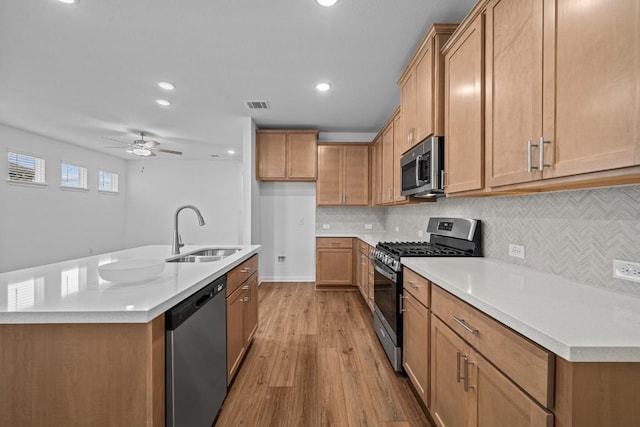 kitchen featuring ceiling fan, sink, stainless steel appliances, and an island with sink