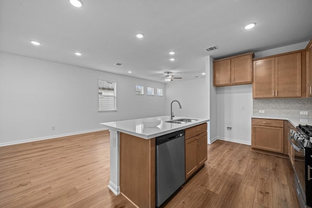 kitchen featuring a center island with sink, sink, light hardwood / wood-style flooring, ceiling fan, and stainless steel appliances