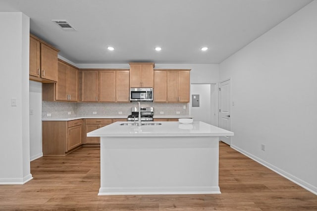 kitchen featuring a center island with sink, stainless steel appliances, light wood-type flooring, and sink