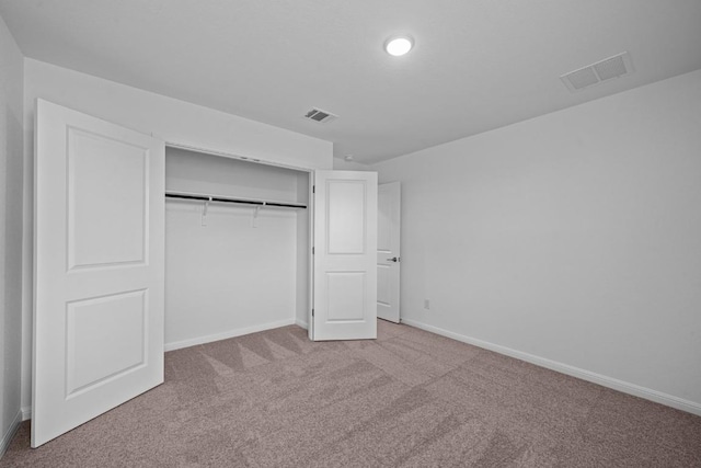 unfurnished bedroom with light colored carpet and a closet