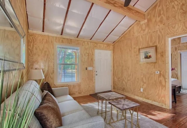 living room with lofted ceiling with beams, hardwood / wood-style flooring, and wood walls