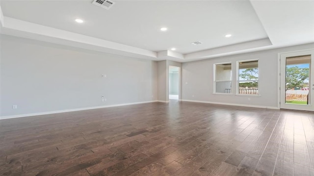 spare room featuring dark hardwood / wood-style flooring and a tray ceiling