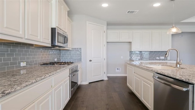 kitchen with sink, stainless steel appliances, dark hardwood / wood-style floors, decorative light fixtures, and white cabinets