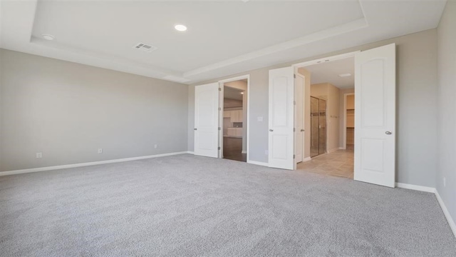 unfurnished bedroom with a raised ceiling and light carpet