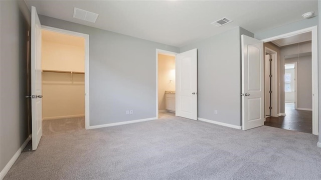 unfurnished bedroom featuring a spacious closet, light carpet, and a closet