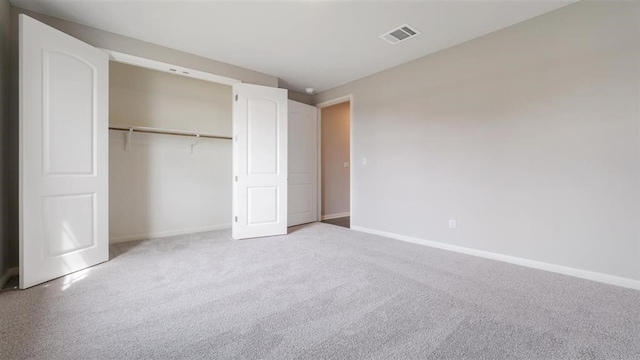 unfurnished bedroom featuring light carpet and a closet