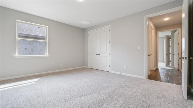 unfurnished bedroom with dark colored carpet and a closet