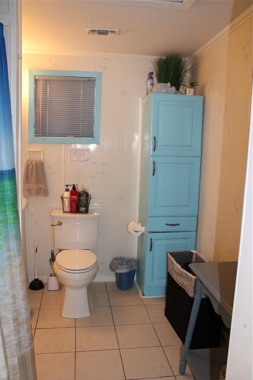 bathroom with tile patterned floors, toilet, and crown molding