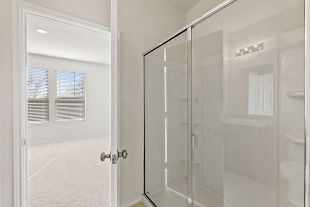 bathroom featuring toilet and a shower with shower door